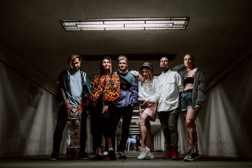 Fashionable group of six adults posing stylishly in an urban underground setting.